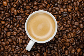 top view of delicious coffee in white cup on fresh coffee grains