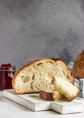 Toasted white artisan bread with butter and jam on light grey stone table. Simple breakfast.