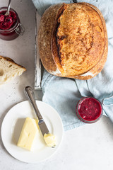Toasted white artisan bread with butter and jam on light grey stone table. Simple breakfast.