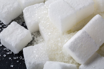Closeup of granulated and sugar cube on black background