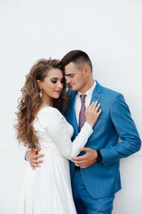 Cute couple embracing looking one to another on dating. A love story. Romantic moment. Happy girl in white dress and guy posing in blue suit and tie.