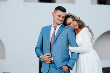 A love story, a walk through the castle. Cute romantic couple having fun outdoors. Beautiful woman in a long white dress walks around the  castle with her husband in a blue suit 