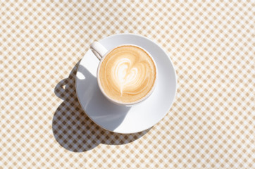 A cup of coffee on the table with a checkered tablecloth.