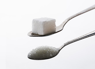 Spoon with granulated sugar and Sugar cube in spoon on white background