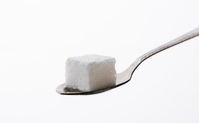 Sugar cube in spoon on white background
