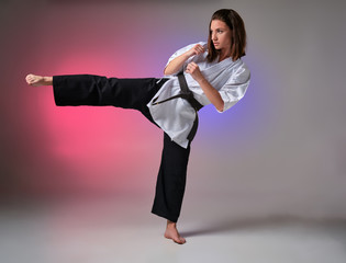 Athletic woman in traditional kimono is practicing karate in studio. © nazarovsergey