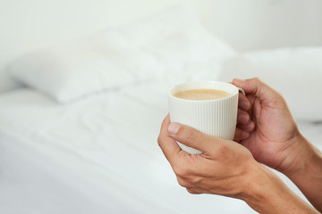 man having a coffee in a bedroom