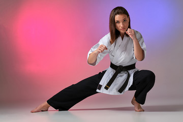 Athletic woman in traditional kimono is practicing karate in studio. © nazarovsergey