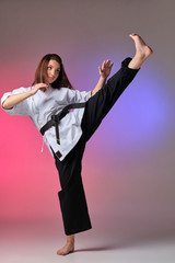 Athletic woman in traditional kimono is practicing karate in studio. © nazarovsergey