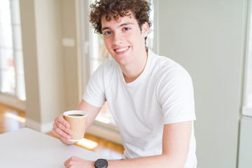 Fototapeta na wymiar Young man drinking take away cup of coffee at home with a happy face standing and smiling with a confident smile showing teeth