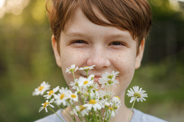 Smiling child with a bouquet of white daisy.