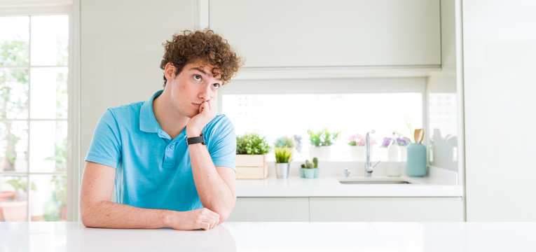 Wide shot of young handsome man at home thinking looking tired and bored with depression problems with crossed arms.