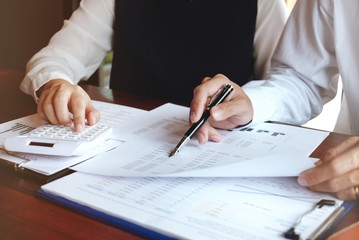 Businessman analyzing investment charts and pressing calculator buttons over documents. Accounting Concept.
