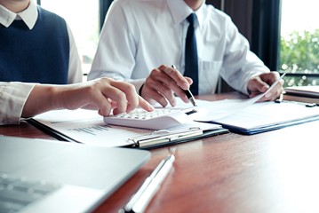 Businessman analyzing investment charts and pressing calculator buttons over documents. Accounting Concept.