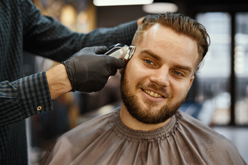 a guy doing a haircut and styling a beard 