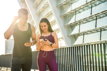 Multiethnic couple relax from exercise by choosing and listening music on smartphone, copy space