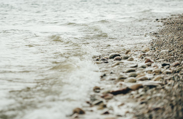 Fototapeta na wymiar Pebble stones on sandy river bank. Closeup