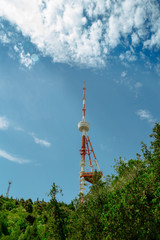 Obraz premium TV tower. Blue sky with clouds. Green trees