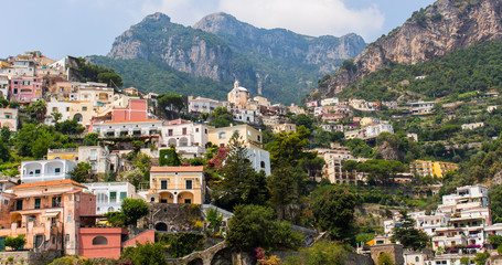 Fototapeta na wymiar Colorful houses, church and blue sky of Positano, in Italy (Campania). This town is built on the cliff of the mountain, along the Amalfi Coast. Shot taken a sunny summer day. – Image