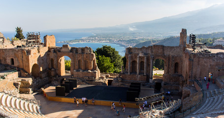 Fototapeta premium Ruins of the antique greek theater of Taormina in Sicily, with the smoking Etna in the background. Sunny summer day in Giardini-Naxos bay on the Ionian see. – Image