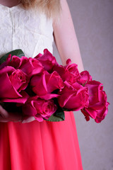 Big bouquet of pink roses held by a young woman wearing a dress