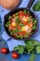 Shakshuka with tomato sauce and quail eggs topped with cilantro in a cast iron pan