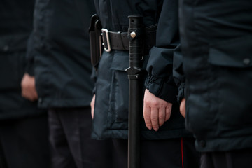 Russian police officers patrolling the street, rear view. Police officer holding a metal detector, security check.