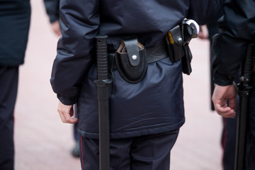 Russian police officers patrolling the street, rear view. Police officer holding a metal detector, security check.