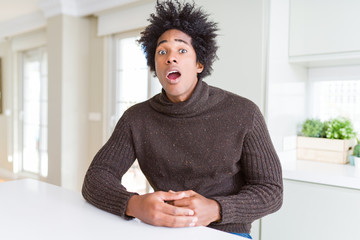 African American man wearing winter sweater afraid and shocked with surprise expression, fear and excited face.