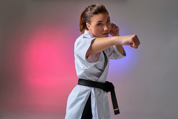 Athletic woman in traditional kimono is practicing karate in studio. © nazarovsergey