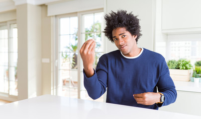 Young african american man wearing casual sweater sitting at home Doing Italian gesture with hand and fingers confident expression