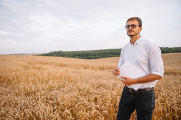 young farmer engineer standing on wheat field