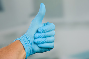 man's hand in medical gloves shows thumbs up
