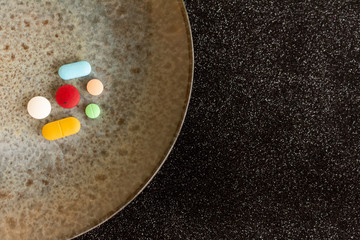 Obraz na płótnie Canvas Colored pills or medications on a plate. Health concept. Copy space Legal drugs of the pharmaceutical industry.