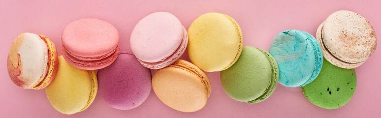 top view of fresh delicious French macaroons on pink background, panoramic shot