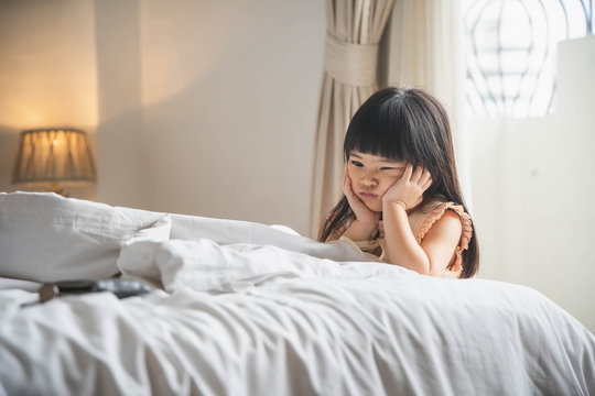 Little asian girl feel boring on bed. Depressed little girls sitting on the bed in sad moody. sad little girl.