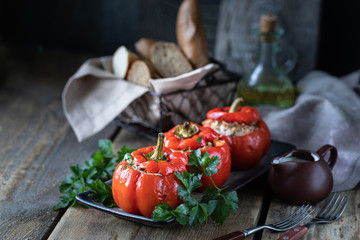 Red pepper stuffed with meat in a black pan on a wooden table.