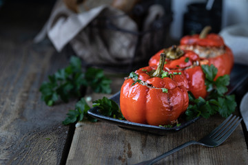 Red pepper stuffed with meat in a black pan on a wooden table.