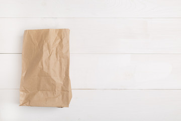 Brown Paper bag on wooden white background with empty space for text. Flat lay, top view.