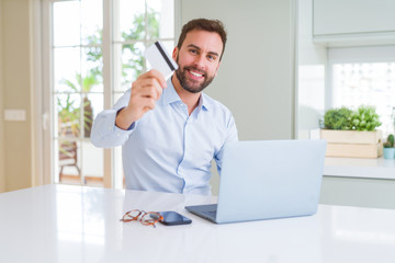 Handsome business man shopping online using computer laptop and credit card