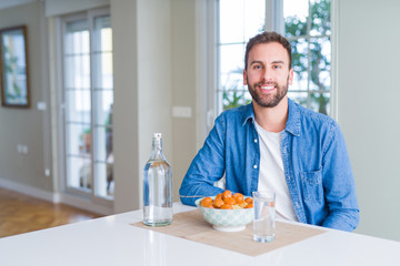 Handsome man eating pasta with meatballs and tomato sauce at home with a happy and cool smile on face. Lucky person.