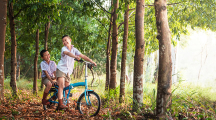 kids riding bike in rural thailand; Children playing in rice field countryside of asia.
