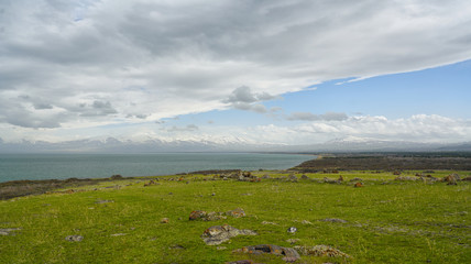 Deserted shore covered with short green grass and gray sea water to the horizon