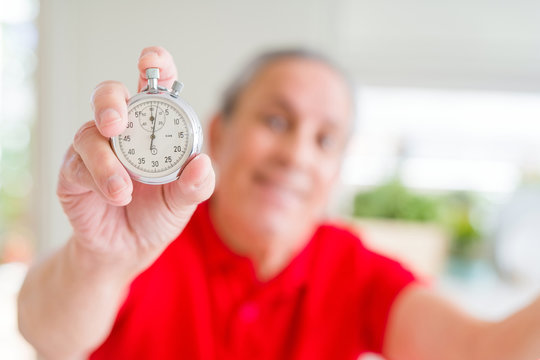 Handsome senior man holding stopwach showing countdown very happy and excited, winner expression celebrating victory screaming with big smile and raised hands