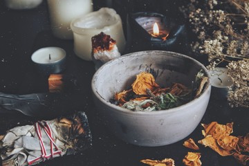 Close up of dried plants, herbs and yellow rose flower petals in a grey, dirty clay pot. Wiccan...