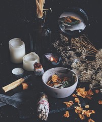 Dried plants, herbs and yellow rose flower petals in a grey, dirty clay pot. Wiccan witch altar...