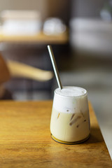 Refreshing iced latte coffee in a glass with straws on wooden table cafe background