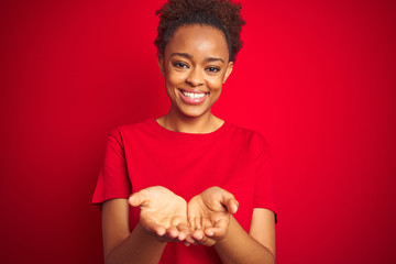 Young beautiful african american woman with afro hair over isolated red background Smiling with...