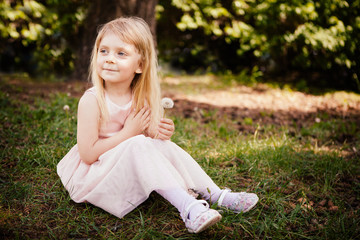 Fototapeta premium Beautiful little girl smiling with dandelion flower in hand, child in summer