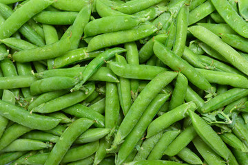 Fresh pea pods as background. Top view.